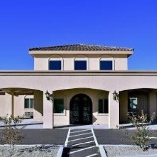 A modern building with an arched entrance and a tiled roof under a clear blue sky.