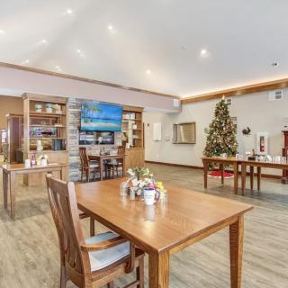 A cozy dining area with wooden tables and chairs, decorated for the holidays with a Christmas tree and festive ornaments.