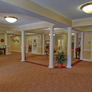 A spacious hallway with columns, carpet, and decorative lighting.