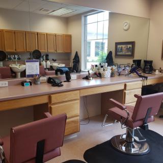 An empty barbershop with chairs and mirrors along a counter.