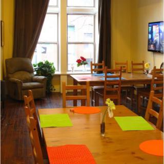 A cozy dining room with wooden furniture and colorful placemats, featuring a television and large windows.