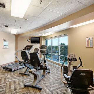 A modern gym with various fitness equipment and large windows.