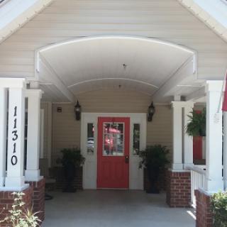 A charming home entrance featuring a vibrant red door and welcoming porch.