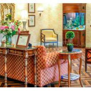 A cozy living room with elegant furniture, floral decorations, and an aquarium in the corner.