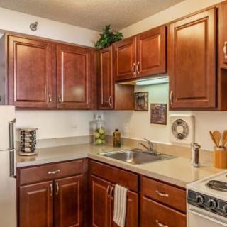 A cozy kitchen with wooden cabinets, a countertop, sink, and stove.