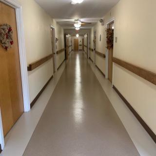 A long, empty corridor with multiple doors and bright overhead lighting.
