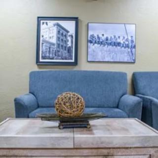 A cozy living room with blue sofas and framed artwork on the wall.