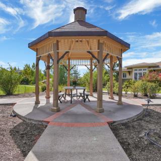 A picturesque gazebo surrounded by a garden under a clear blue sky.