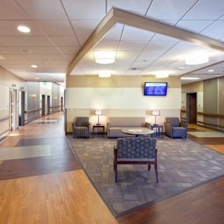 A modern hospital waiting area with comfortable seating and a television.
