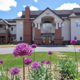 A beautiful residential building surrounded by blooming flowers under a clear blue sky.