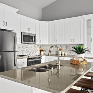 A contemporary kitchen featuring sleek white cabinetry, stainless steel appliances, and a stylish island with grey countertops.