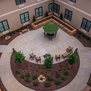 Aerial view of a landscaped courtyard featuring outdoor seating with chairs and an umbrella.