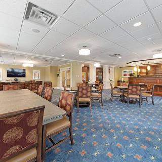 A well-lit dining area with tables and chairs, featuring elegant decor and patterned carpeting.