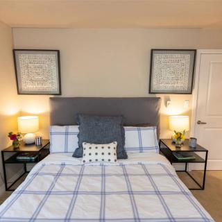 A neatly arranged bedroom featuring a bed with a checkered duvet, flanked by two nightstands and lamps.