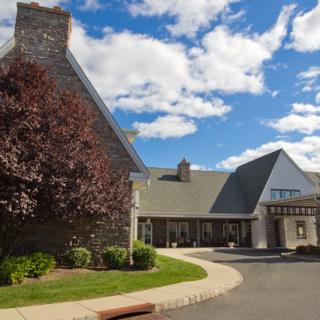 A scenic view of a building with a stone facade and pointed roof under a partly cloudy sky.