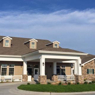 A large residential building with a covered porch and multiple dormer windows.
