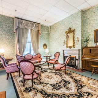 A vintage living room with antique furniture and a piano.