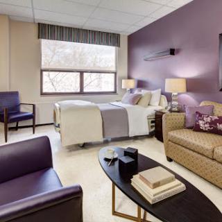 A modern and comfortable hospital room featuring a cozy bed, seating area, and stylish decor.