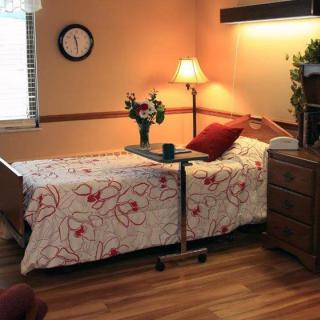A cozy bedroom with a single bed, decorated with floral bedding and accompanied by a bedside table and lamp.