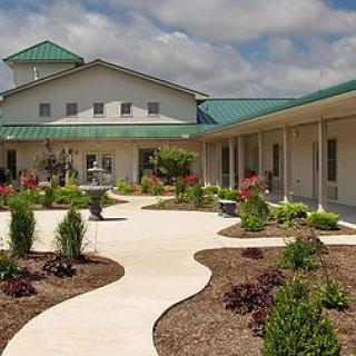 A building with a green roof surrounded by a landscaped courtyard and walkway.