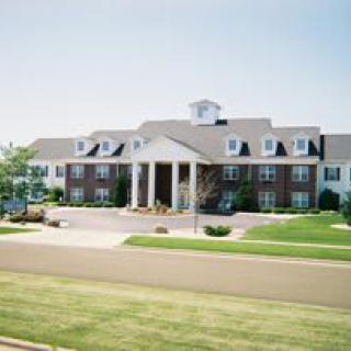 A large colonial-style building with manicured lawns in a suburban setting.