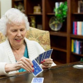 An elderly woman enjoying a game of cards in a library setting.