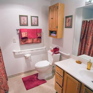 A neatly organized bathroom featuring a toilet, sink, and shower with red accents.