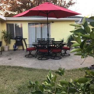 A cozy backyard patio with a red umbrella and outdoor dining set.