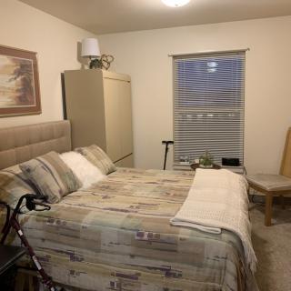 A cozy bedroom with a neatly made bed, artwork on the wall, and soft lighting.