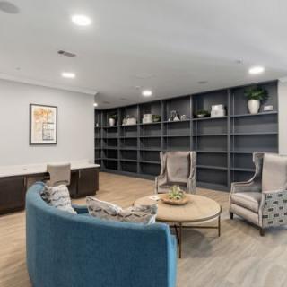 A modern office lounge area with comfortable seating and extensive shelving.