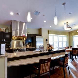 A modern kitchen with stainless steel appliances, a large countertop, and adjacent dining area.