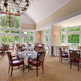 A bright dining room with elegant furnishings and large windows allowing natural light to fill the space.