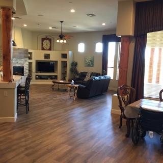 Spacious living room with an open floor plan featuring wood flooring, a comfortable sofa, and a dining area.