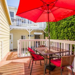 A cozy outdoor patio with a red umbrella and seating area.