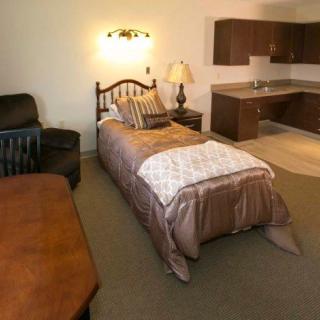 A cozy room with a single bed and kitchenette area.