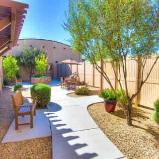 A beautifully landscaped backyard featuring a desert garden with trees, a patio area, and outdoor seating.
