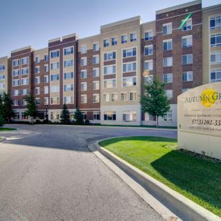 A multi-story residential apartment complex with a well-maintained entrance and green landscaping.