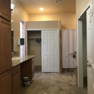 A spacious bathroom featuring a sink area, shower, and storage options.