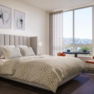 A modern bedroom with a large bed, stylish artwork, and a window offering scenic views.