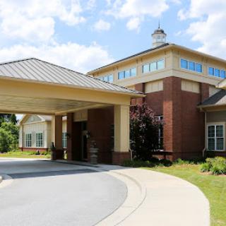 A modern residential building with a welcoming entrance and well-maintained landscaping under a clear blue sky.