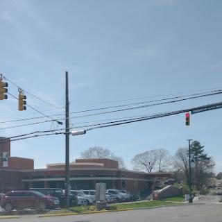 A view of a busy intersection with traffic lights and nearby buildings under a clear sky.