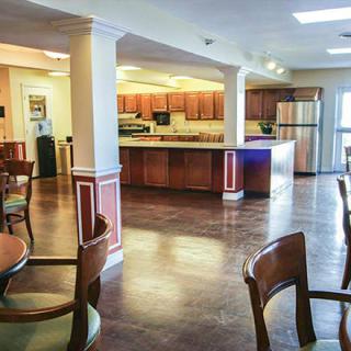 A modern kitchen and dining area with wooden cabinets, tables, and chairs in an open space.