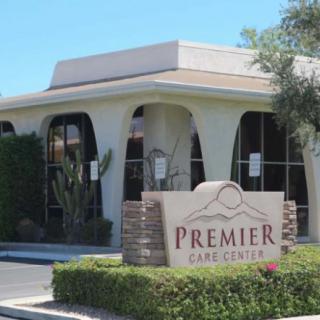 The image shows a commercial building with a sign reading 'Premier Care Center' surrounded by greenery.