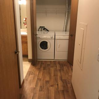 A compact laundry area with a washer and dryer set, featuring wood flooring.