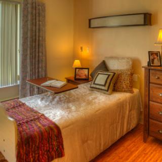A cozy and inviting bedroom featuring a neatly made bed, soft lighting, and warm decor.