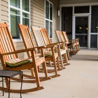 A row of wooden rocking chairs on a porch.