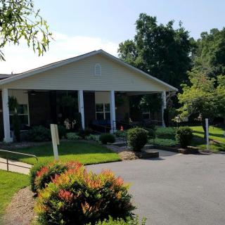 A charming house with a well-maintained front yard and driveway, surrounded by lush greenery.