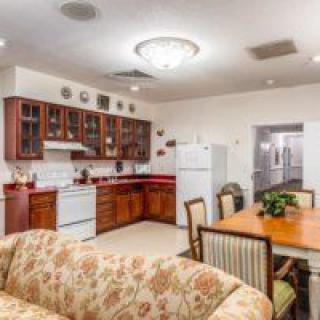 A cozy open-concept kitchen and dining area with wooden cabinets, dining table, and a floral sofa.