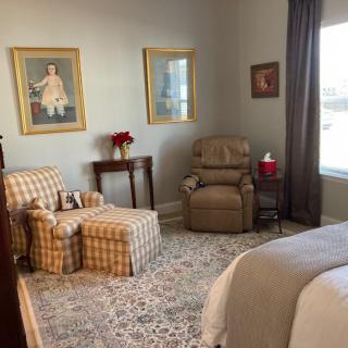 A cozy bedroom with an armchair, recliner, and decorative elements.