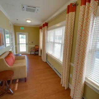 A cozy hallway with a couch, large windows, and decorative curtains.